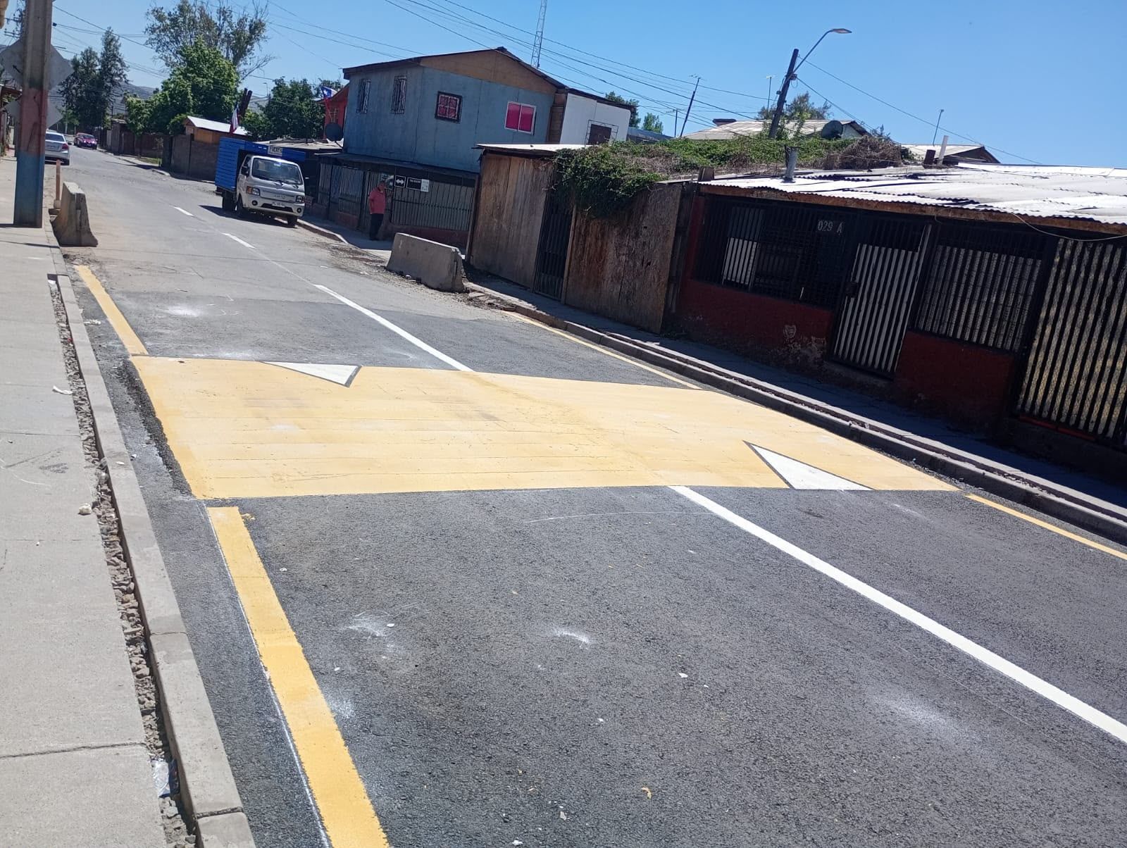 Calle pavimentada con demarcación vial y cruce peatonal